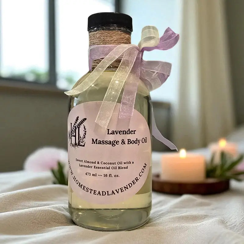 A 16 fl. oz. clear glass bottle of lavender massage oil with candles and sprigs of lavender