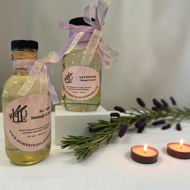 A 8 & 16 fl. oz. clear glass bottle of lavender massage oil with candles and sprigs of lavender