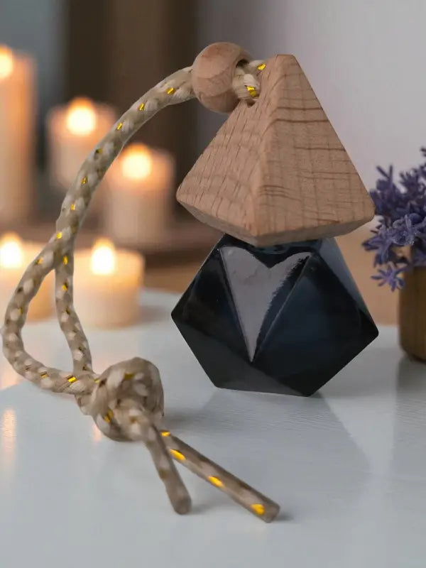 Glass lavender car diffuser bottle with wooden top and rope, styled with lavender flowers and candles on a light wood surface, created at Homestead Lavender Farm.