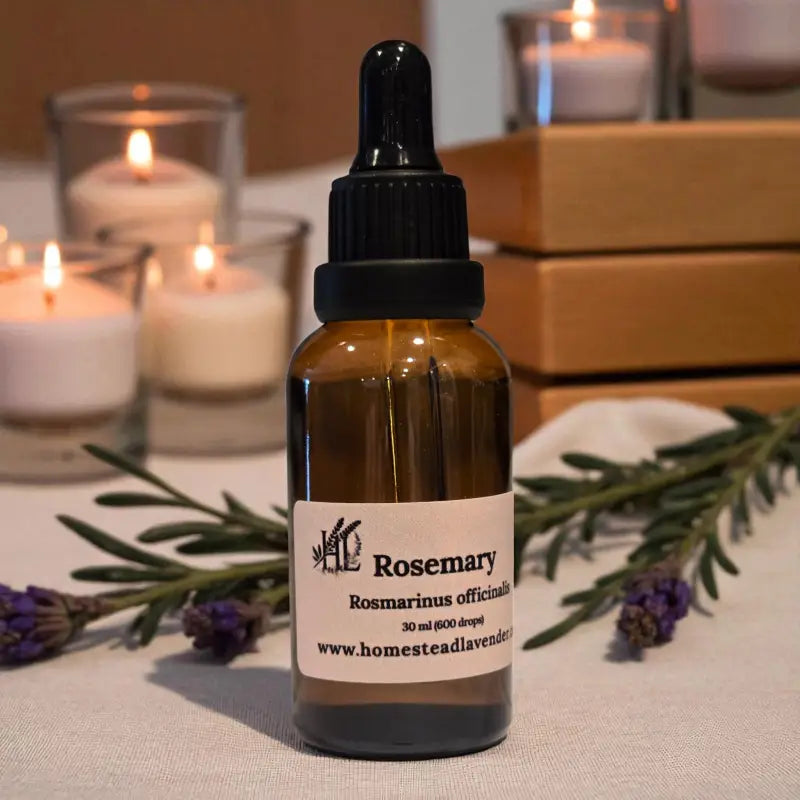 Amber dropper bottle of rosemary essential oil beside candles and lavender – handcrafted on our Homestead Lavender Tennessee farm.