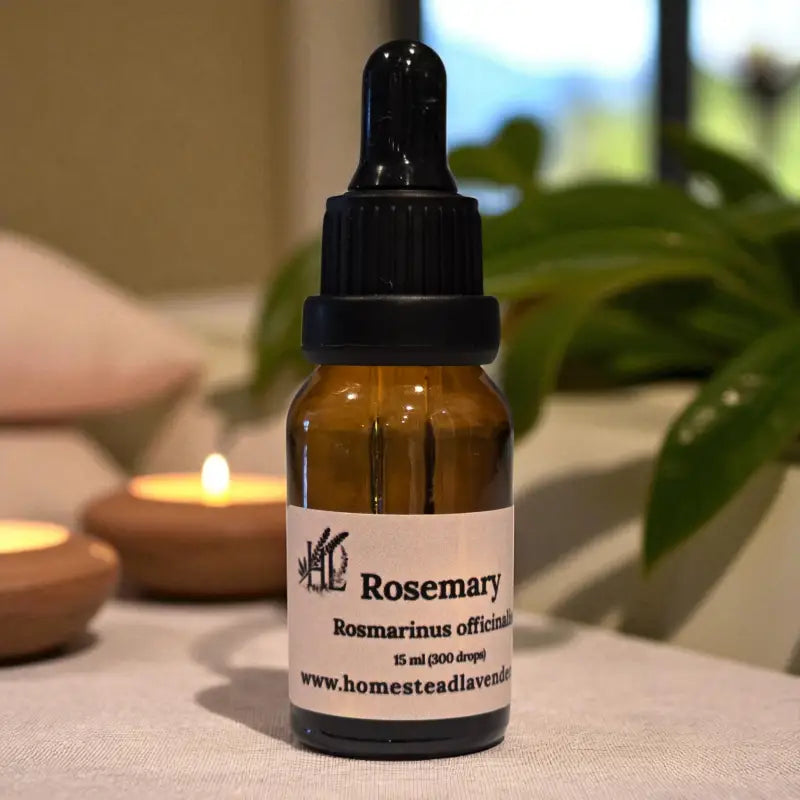 Amber dropper bottle of rosemary essential oil beside candles and lavender – handcrafted on our Homestead Lavender Tennessee farm.