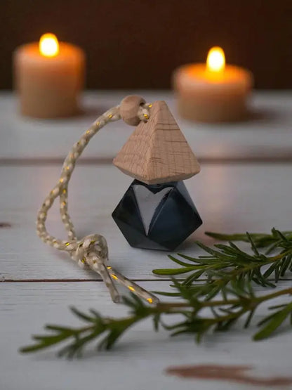 Glass rosemary car diffuser with wooden cap, styled with rosemary sprigs and candles on a light wood surface Homestead Lavender Farm.