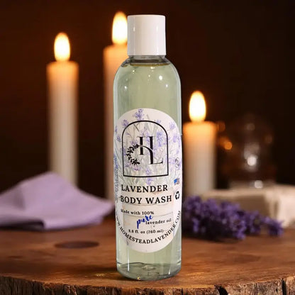 8.8 fl. oz. bottle of Homestead Lavender Lavender Body Wash sitting on a wooden surface with lit candles in the background.