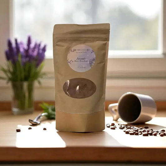 Lavender hot chocolate mix in a kraft pouch, placed on a wooden table with cocoa beans, lavender, and soft morning light.