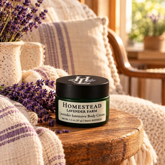 Lavender Intensive Body Cream jar on a side table beside a striped throw and lavender sprigs