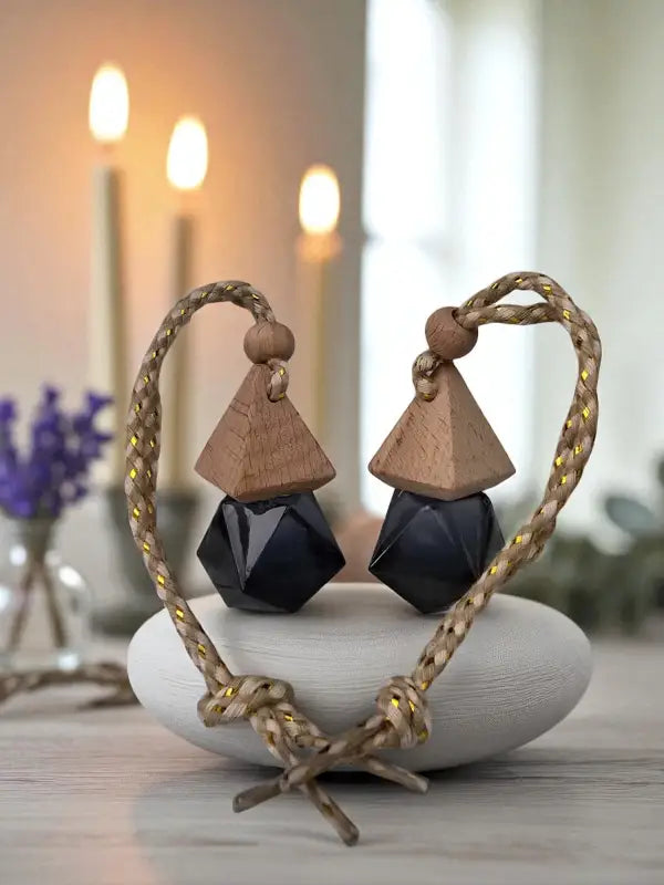 Two decorative glass geometric car diffusers sitting on stone base with lavender flowers and candles in the background, created at Homestead Lavender Farm.